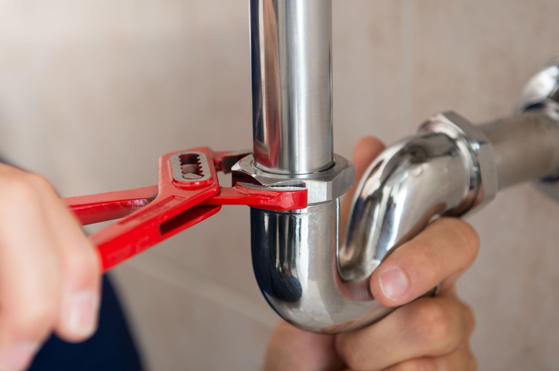 Plumber using a wrench on a drain pipe